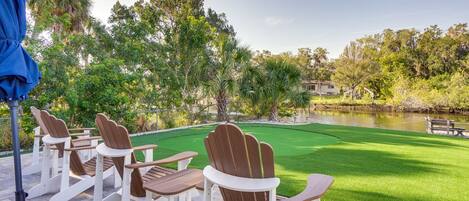 A patio with Adirondack chairs and a view of a golf course.