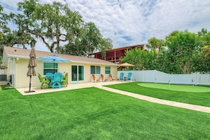 A residential property with a patio area, outdoor seating, and a well-maintained lawn. - Riverfront Home w/ Putting Green & Boat Dock! (New Port Richey)