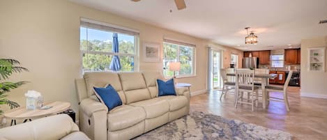 A spacious living room with a beige leather sofa, a coffee table, and a ceiling fan.