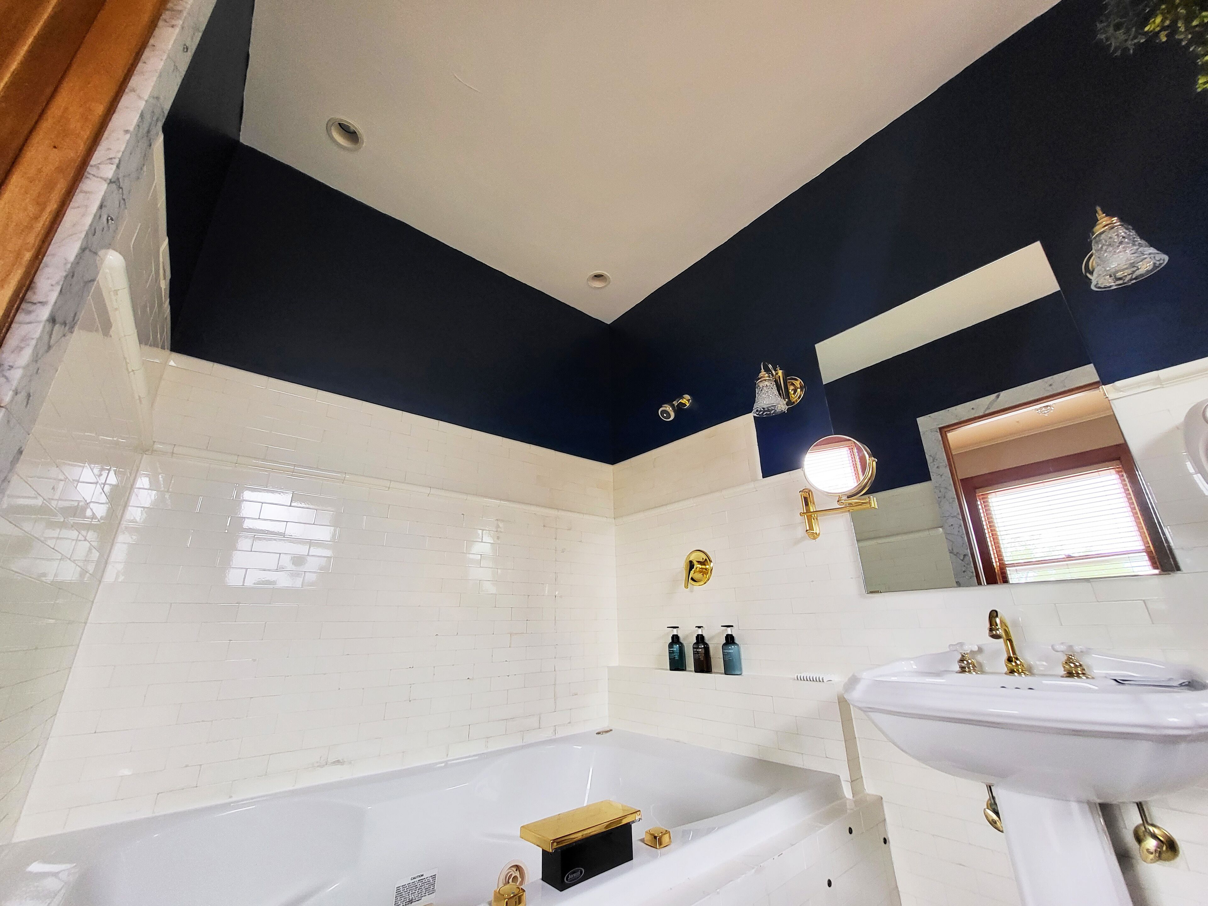 Un baño moderno con una bañera blanca, un lavabo blanco y un techo oscuro.
