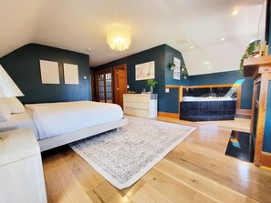A bedroom with a bed, a dresser, a rug, and a bathroom with a bathtub.