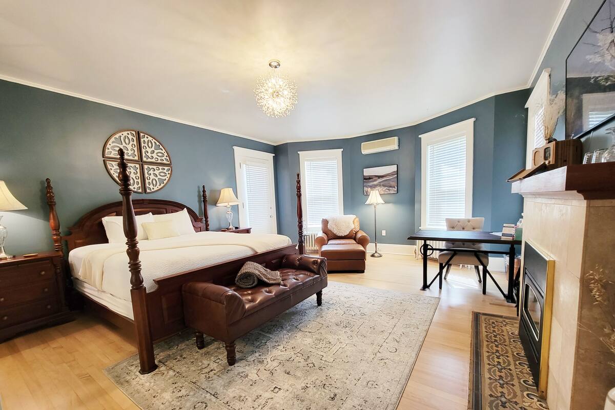 A spacious bedroom with a four-poster bed, a leather sofa, and a dining area.