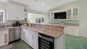 A kitchen with white cabinets, granite countertops, stainless steel appliances, and a green floor. - Heated Pool I Soundproof Home I Firepit I 630Mbps (Hollywood)