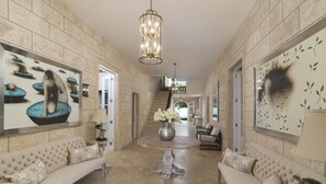 A spacious hallway with a high ceiling, a central round table with a vase of flowers, and two sofas with star-patterned cushions.