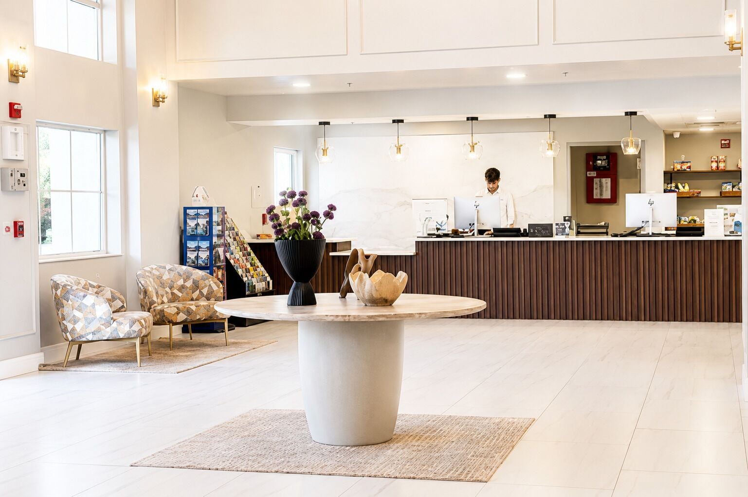 Un hall d’hôtel moderne avec un comptoir d’accueil, un espace salon et une grande fenêtre.