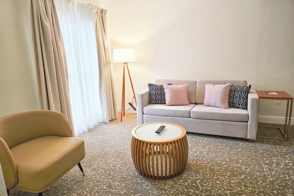 A living room with a sofa, a chair, a round coffee table, a lamp, and a side table.