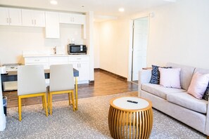 Una sala de estar moderna con un sofá, una mesa de centro y un comedor con sillas y un microondas.