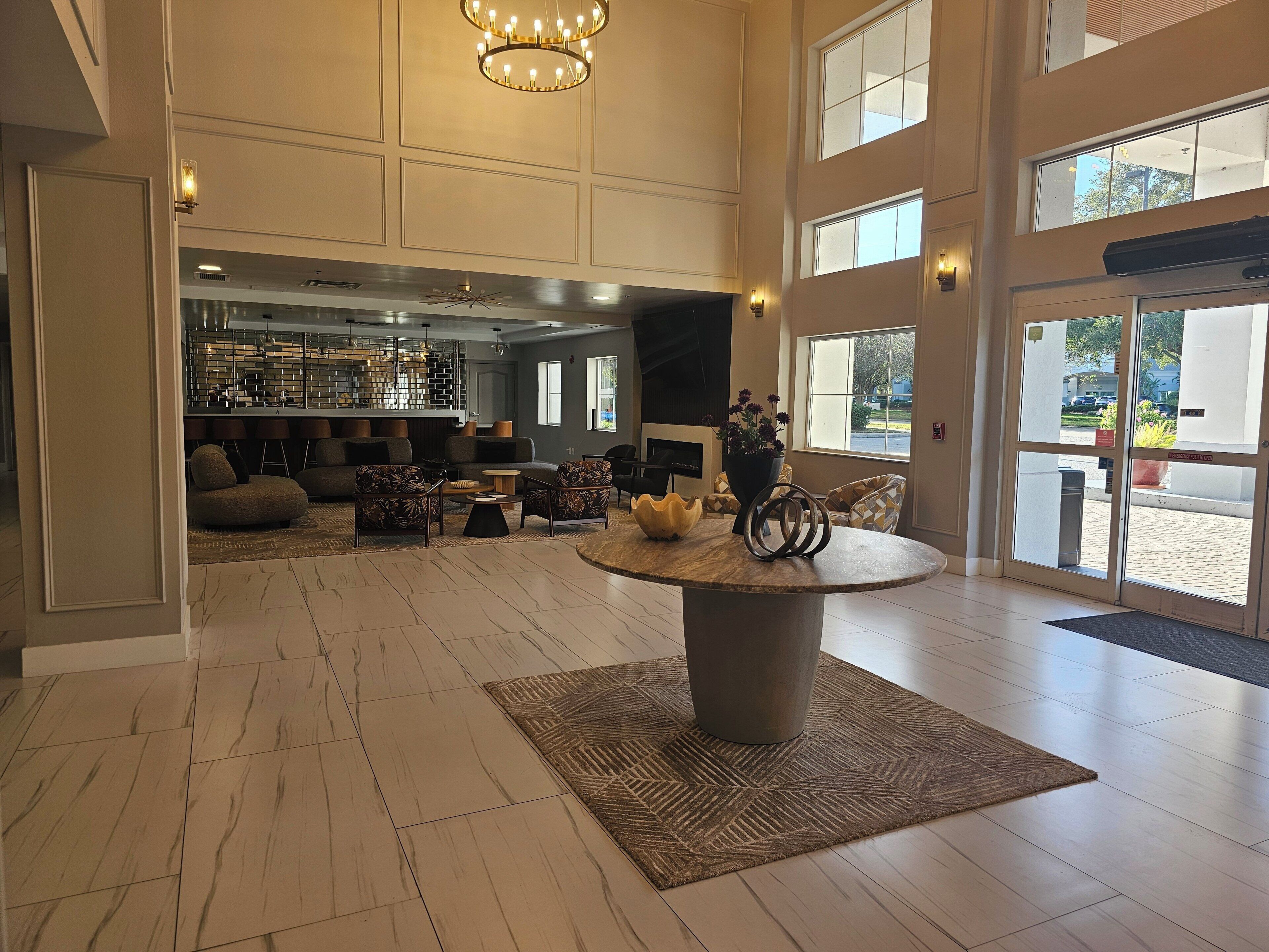A spacious lobby with a central round table, seating area, and a bar.