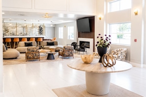 A spacious living area with a fireplace, comfortable seating, and a modern kitchen in the background. - MONTREAL SUITES ORLANDO by IHG (Orlando)