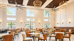 A spacious indoor dining area with multiple tables and chairs, ceiling fans, and pendant lighting fixtures. - MONTREAL SUITES ORLANDO by IHG (Orlando)