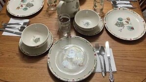 A dining table set with plates, bowls, glasses, and cutlery. - Cozy 3-bedroom 2 bathroom house (Russell)