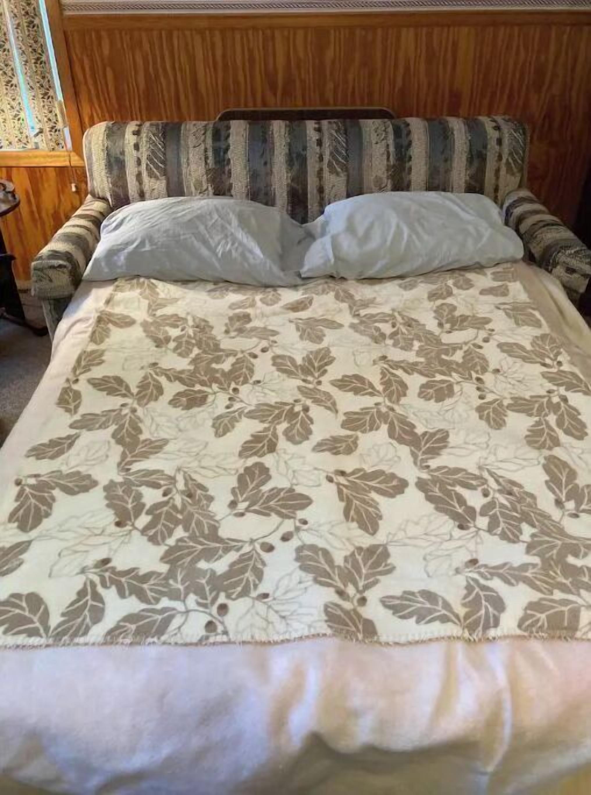 A bed with a floral-patterned bedspread and two pillows.