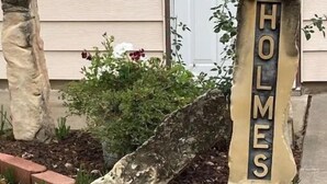 A house with a sign that reads "HOLMES" in front of a white door. - Cozy 3-bedroom 2 bathroom house (Russell)