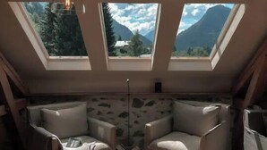 Ein Zimmer mit zwei Oberlichtern, einer Pendelleuchte und zwei Sesseln.