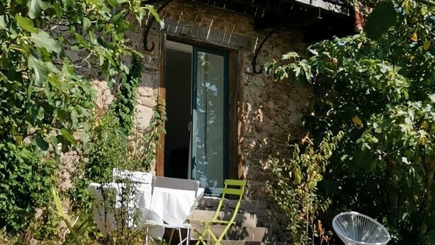 A stone house with a balcony, a dining table with chairs, and a chair outside. - Centaurée** - Charm and countryside at a Witch on the Roof (Firmi)