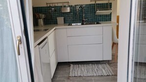 A compact kitchen with white cabinetry, a tiled backsplash, and a small island. - Centaurée** - Charm and countryside at a Witch on the Roof (Firmi)