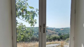 A room with a sliding glass door leading to an outdoor area with a view of a hilly landscape. - Centaurée** - Charm and countryside at a Witch on the Roof (Firmi)
