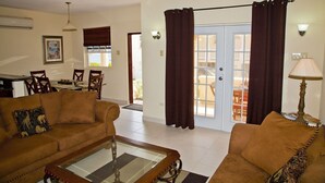 A living room with a sofa set, a coffee table, and a dining area with chairs and a table.