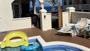 A pool area with a hot tub, lounge chairs, and a children's inflatable pool.