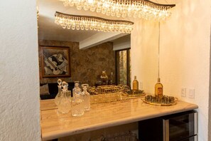 A bar area with a wooden countertop, a chandelier, and various glassware and bottles.