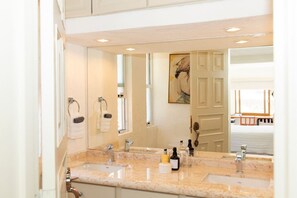 Un baño con dos lavabos, un espejo grande y una puerta que da a una habitación con vistas.