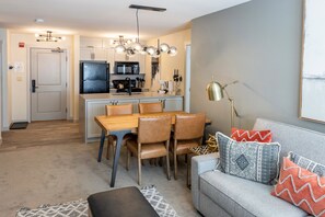 Cozy living area with a central kitchen, dining table, and comfortable sofa.