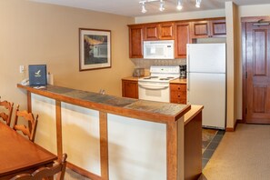 Kitchen area with microwave, stove, and refrigerator, featuring a central island and framed artwork.