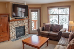 Cozy living room with a stone fireplace, comfortable sofa, and flat-screen TV.