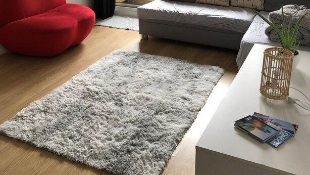 Una sala de estar moderna con una butaca roja, un sofá gris y una mesa de centro blanca con revistas.