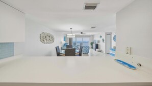 A modern kitchen with a dining area, white walls, and a view of the sea. - Seaside Villa~ Charming Beachfront Condo w/ Pool! (Marathon)