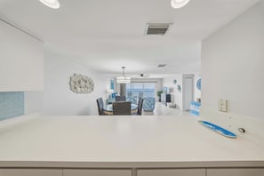 A modern kitchen with a dining area, white walls, and a view of the sea. - Seaside Villa~ Charming Beachfront Condo w/ Pool! (Marathon)