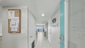 A hotel corridor with a bulletin board, a non-smoking sign, and a view to the outside. - Seaside Villa~ Charming Beachfront Condo w/ Pool! (Marathon)