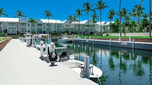 A marina with boats docked, a waterway, and a row of hotel buildings with balconies. - Indigo Reef #50 ~ The Palms, Sunset Views & 31' Boat Slip (Marathon)