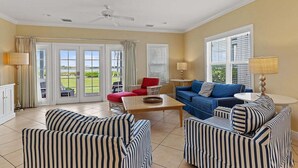 A spacious living room with striped sofas, a red chair, a blue sofa, and a ceiling fan. - Indigo Reef #50 ~ The Palms, Sunset Views & 31' Boat Slip (Marathon)