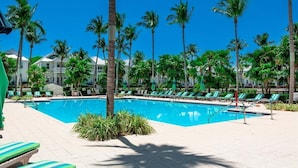 A swimming pool with lounge chairs and palm trees. - Indigo Reef #50 ~ The Palms, Sunset Views & 31' Boat Slip (Marathon)