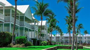 A beachfront hotel with multiple balconies, palm trees, and a clear blue sky. - Turtle Cove at Indigo Reef~ Pet-friendly Townhome, 31' Boat Slip! (Marathon)