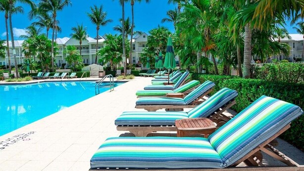 A poolside area with lounge chairs and palm trees. - Turtle Cove at Indigo Reef~ Pet-friendly Townhome, 31' Boat Slip! (Marathon)