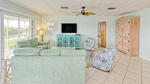A living room with a sofa, a cabinet, a television, and a ceiling fan. - One Particular Harbor ~ Waterfront Pool Home Near the Beach! (Marathon)