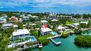 An aerial view of a coastal residential area with houses, a marina, and a swimming pool. - One Particular Harbor ~ Waterfront Pool Home Near the Beach! (Marathon)