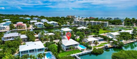 Vista aérea de una zona residencial costera con casas, un puerto deportivo y una piscina.
