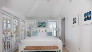 Ein Schlafzimmer mit einem großen Bett, einer Bank, einem Nachttisch und einem Fenster mit Jalousien.
