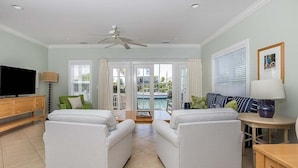 Ein Wohnzimmer mit zwei weißen Sofas, einem Fernseher und einem Deckenventilator.