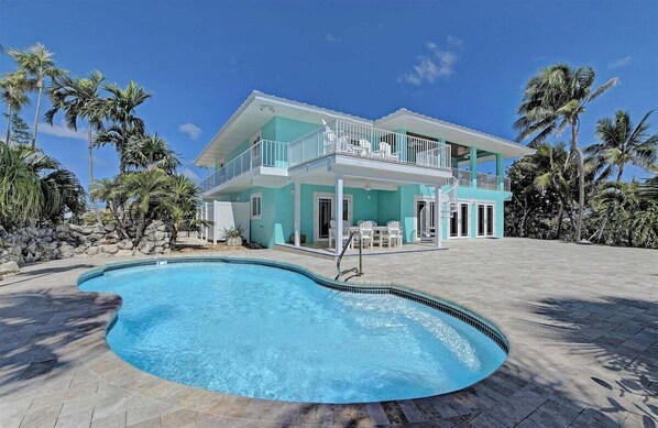 A two-story house with a swimming pool in front.