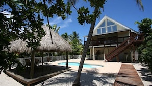 A resort with a pool, a thatched-roof structure, and a wooden deck. - Kon Tiki ~ Private Waterfront Pool Home, 30' Dock (Marathon)