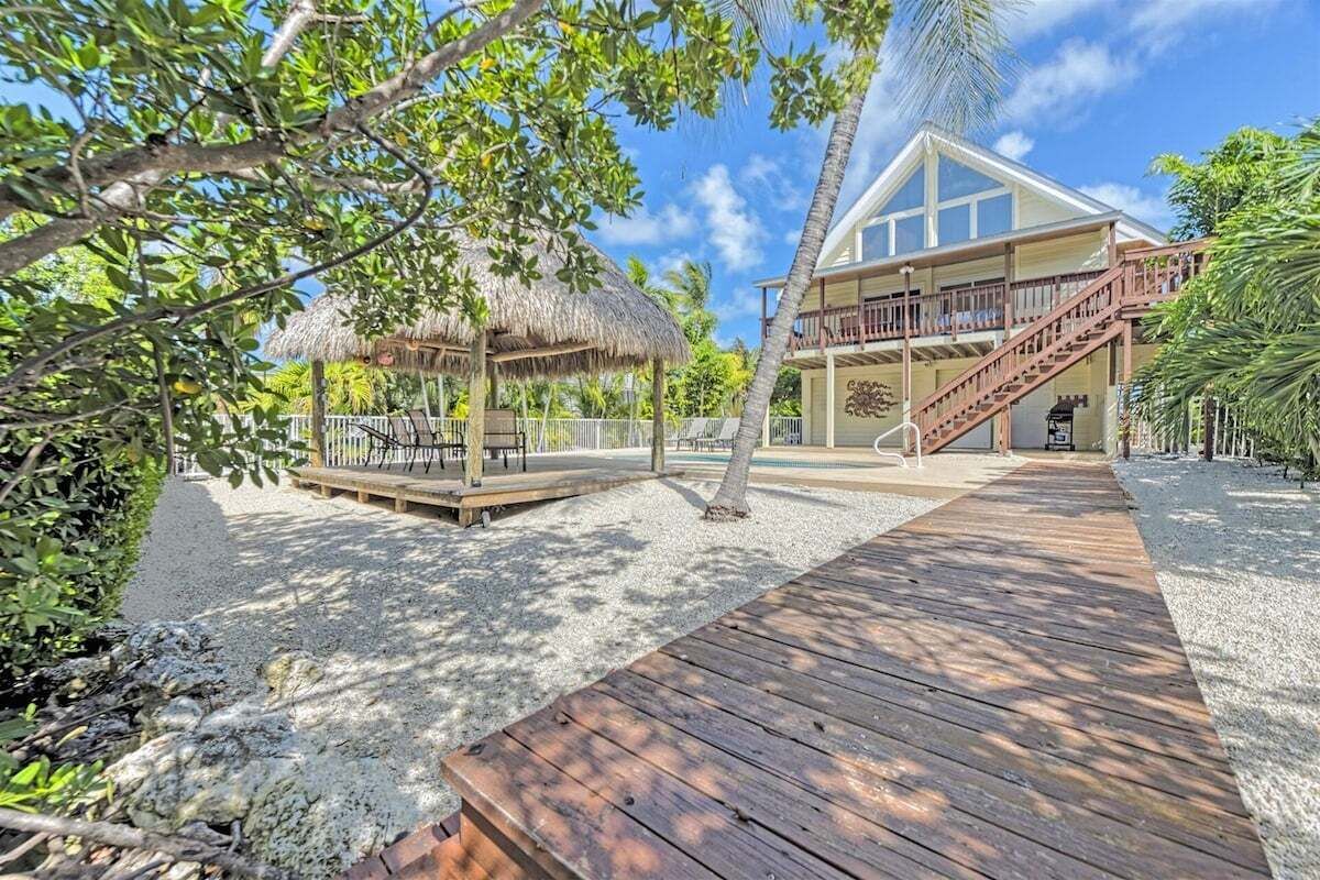 A resort with a wooden deck, a thatched-roof structure, and a building with a balcony.
