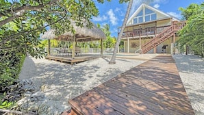 A resort with a wooden deck, a thatched-roof structure, and a building with a balcony. - Kon Tiki ~ Private Waterfront Pool Home, 30' Dock (Marathon)