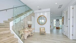 A modern interior with a glass staircase, a round mirror, and a wooden floor. - Casa Playa~ Luxury Pool Home Amazing Outdoor Area! (Marathon)