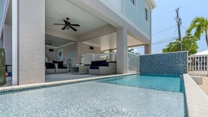 A swimming pool with a tiled wall and a covered seating area with a ceiling fan. - Island Time~ Pool Home Seconds to Open Ocean! 26' Dock (Marathon)