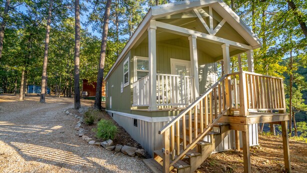 A small cabin with a porch and a wooden staircase leading to a deck.