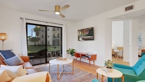 A modern living room with a sofa, coffee table, and a TV mounted on the wall.